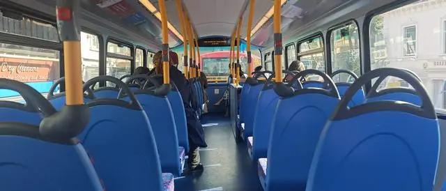 Inside a London double-decker bus during the day.