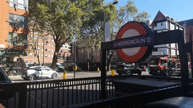 Busy London street with Underground sign and vehicles passing by.
