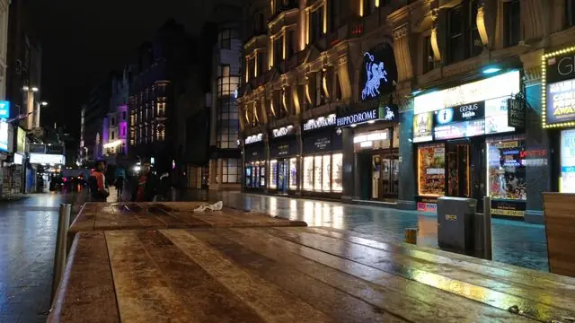 Explore a lively city street at night, filled with shops and lights.