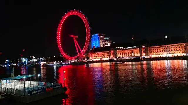 Night view of the illuminated London Eye reflecting on the Thames.