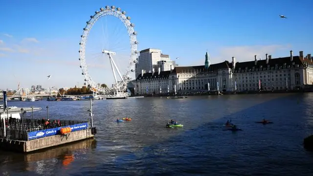 Kayakers paddle on River Thames under a sunny sky near the London Eye.