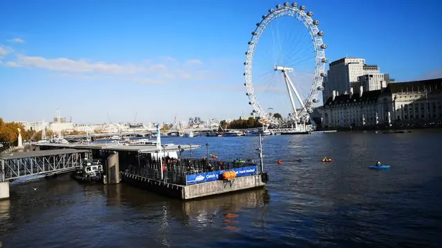 View of the London Eye on a sunny day along the River Thames.