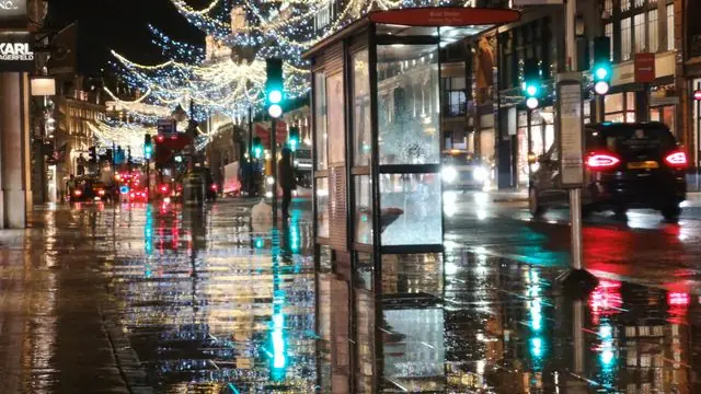 Rainy night in London with Christmas lights reflecting on streets.