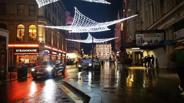 Nighttime urban street with festive lights and bustling activity.