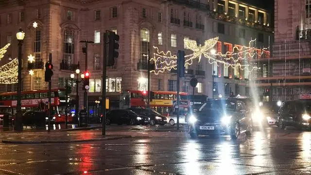 Rain-soaked London streets illuminated by festive Christmas lights.