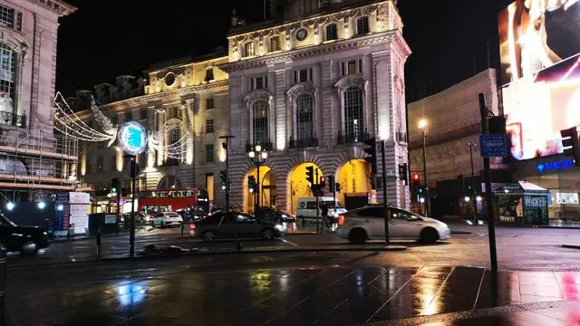 Nighttime city scene in London's rainy streets with lights and traffic.