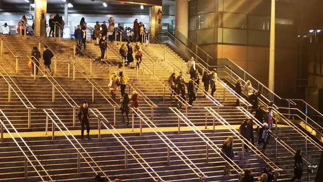 People navigating urban stairs at night under city lights.