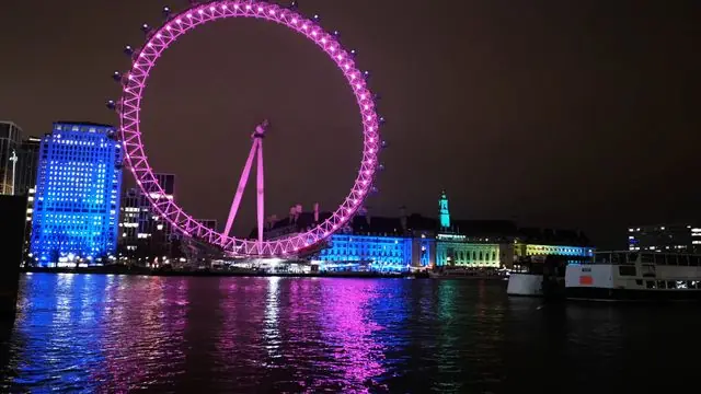 Experience the London Eye illuminated with vivid colors at night along the Thames.