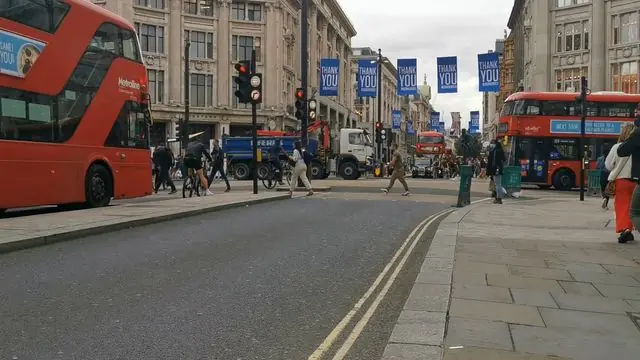 A busy London street with red buses and pedestrians.