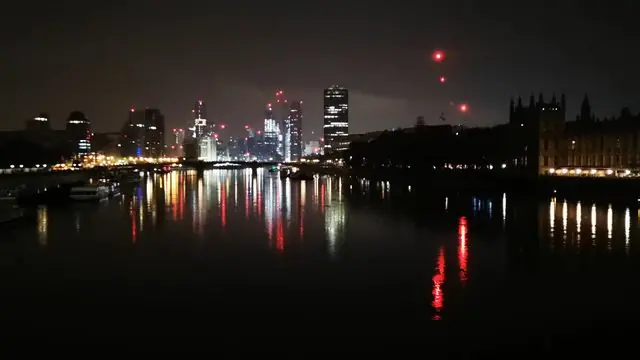 View of London's skyline lights reflecting on the Thames at night.