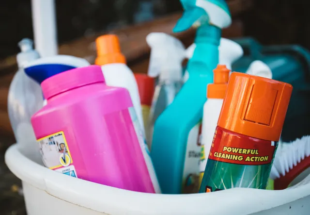 Assorted cleaning supplies in a bucket outdoors